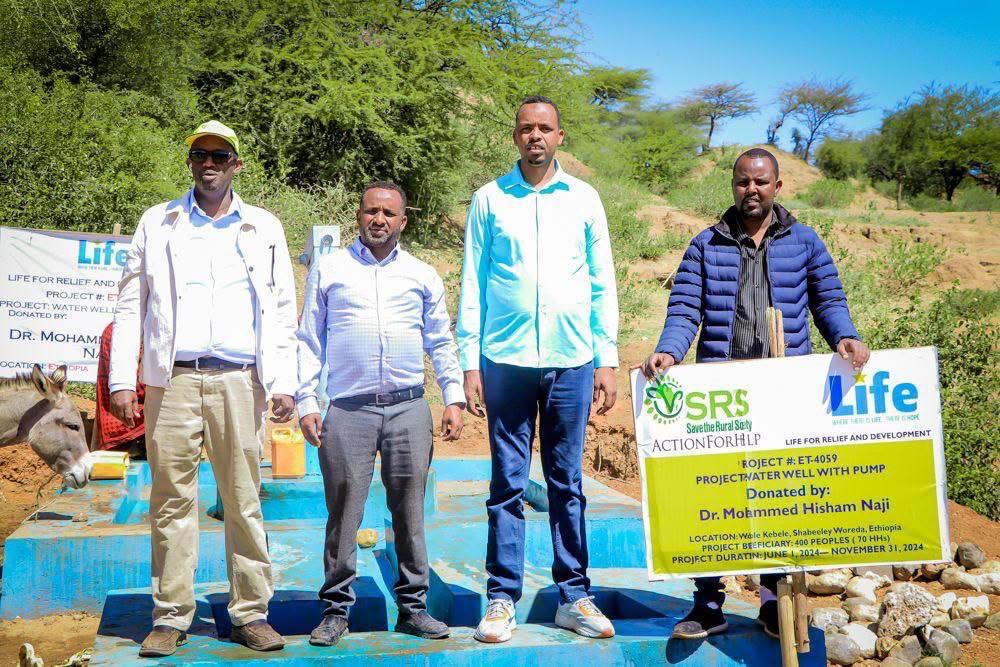 Community members using a new hand pump at an SRS water well opening